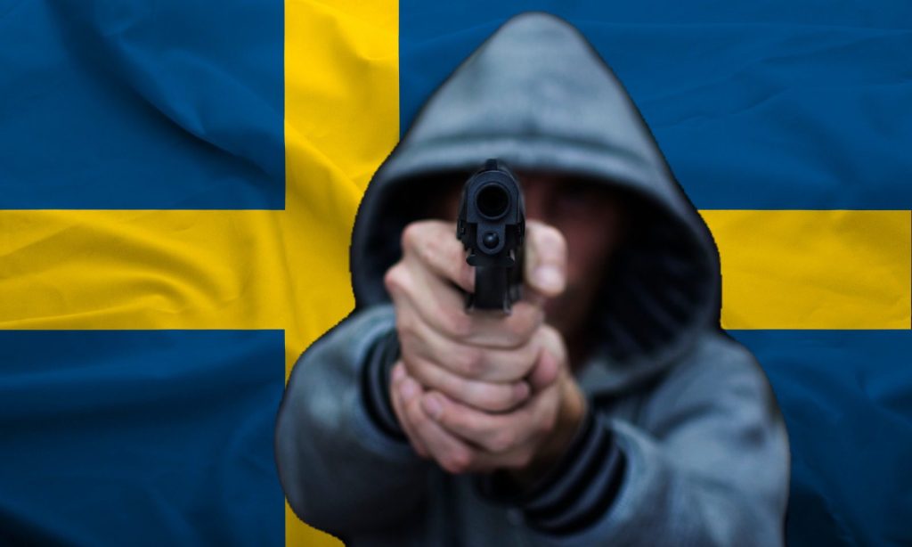 Mann mit Pistole vor schwedischer Fahne